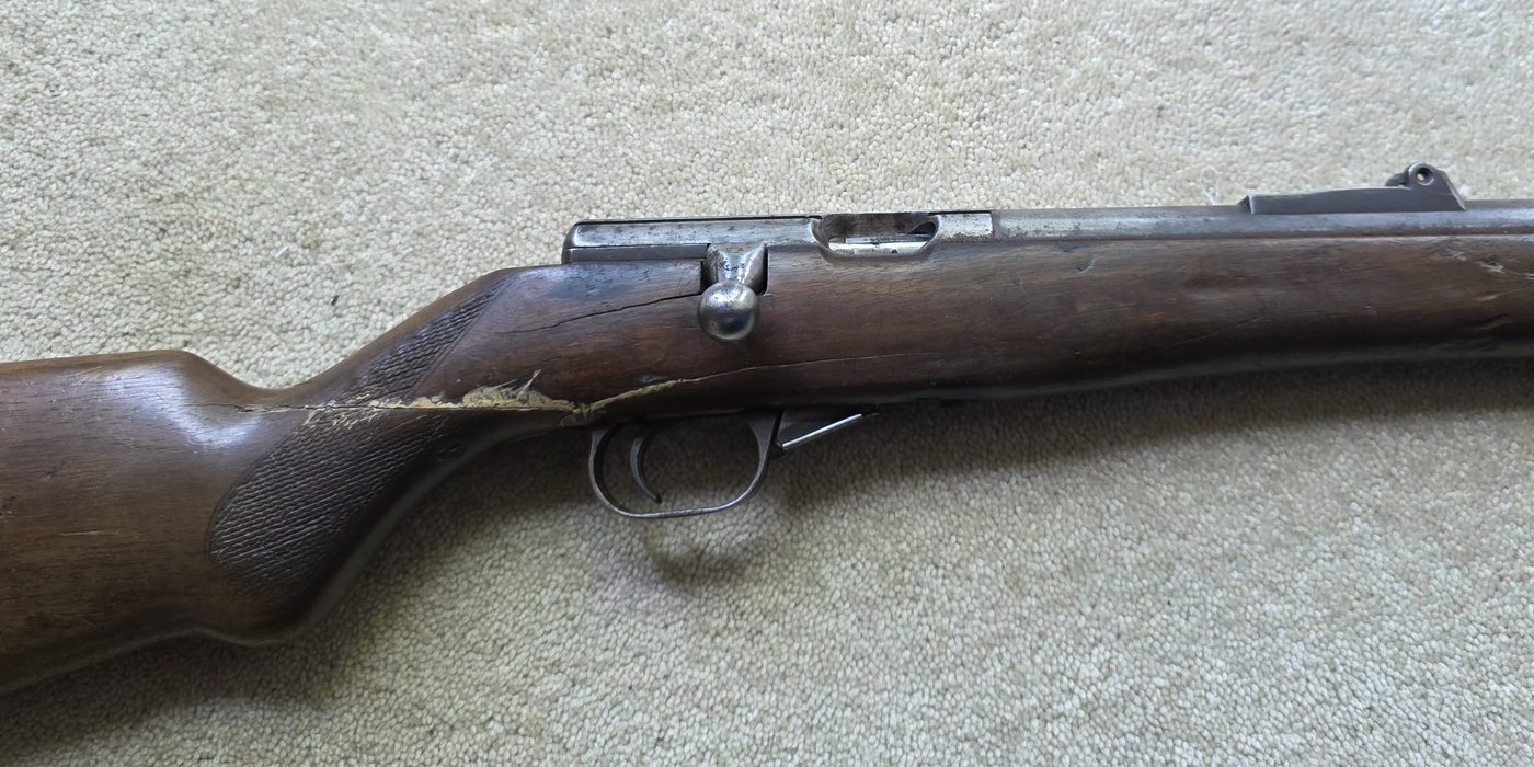 A bolt-action rifle with a split along the wrist of the stock